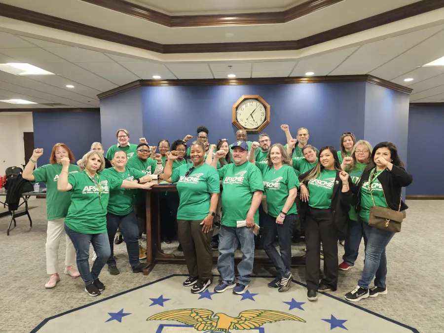 Group of AFSCME members in green shirts standing in front of historic lobbyist's table in NV Legislature