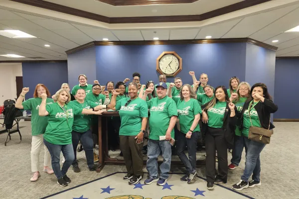 Group of AFSCME members in green shirts standing in front of historic lobbyist's table in NV Legislature